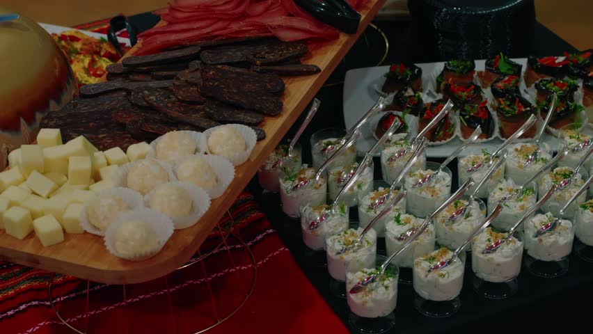 Panning shot of a rich Bulgarian gourmet buffet featuring traditional meats, cheeses, and appetizers at a gala event.