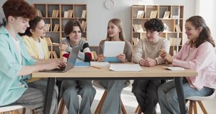 Students teenagers collaborate on group project in classroom. Six peers work as a team at a table with laptop and papers, discussing homework and study ideas. Teamwork and active learning concept. - Powered by Shutterstock - Get 15% off with code: PIKWIZARD15
