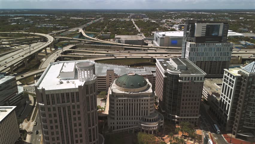 Backward aerial pull away from downtown Orlando skyline and highway