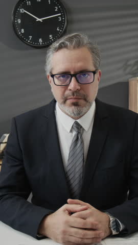 Vertical zoom out portrait of confident middle-aged HR specialist in formalwear posing for camera with smile during workday in office