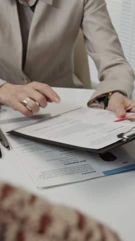Vertical over the shoulder shot of anonymous female hiring manager handing resume to unknown applicant because finding it insufficient