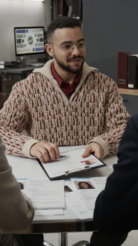 Vertical shot of positive young man thanking two unknown HR managers shaking hands with them after going through job interview in office setting
