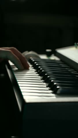 Musician hands moving skillfully across black and white keys of digital piano, creating beautiful melody during performance on dimly lit stage, atmospheric lighting. Musician playing piano keyboard