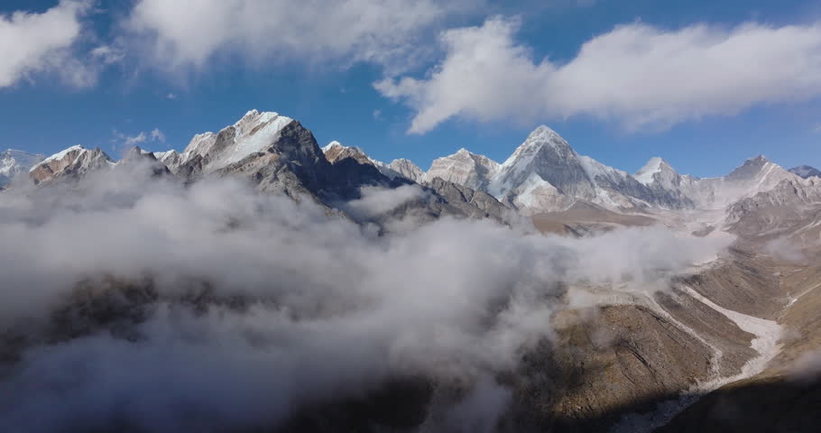 Aerial shot above clouds reveals the Khumbu mountain region in Nepal Everest area, showcasing dramatic Himalayan peaks and alpine landscape.