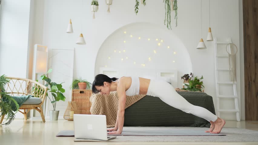 Yoga fitness workout training online. Woman practicing yoga with online lessons in laptop at home. Woman doing sports exercise on yoga mat. Girl have training workout for weight loss. Sport fitness