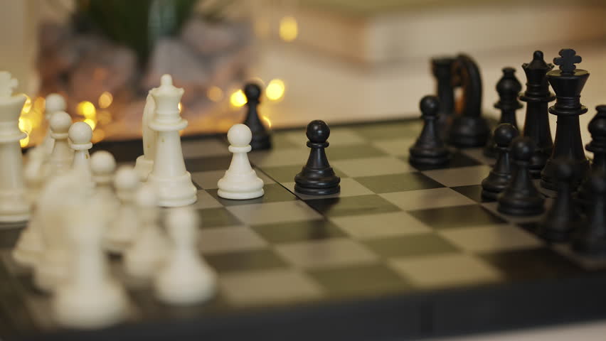 Close-up of woman and man playing chess, moving pieces on wooden board