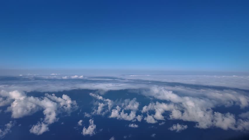A aerial view taken from a jet cockpit while flying over a layer of wispy clouds hanging over the Mediterranean sea. Fast motion shot accelerated 5 times.