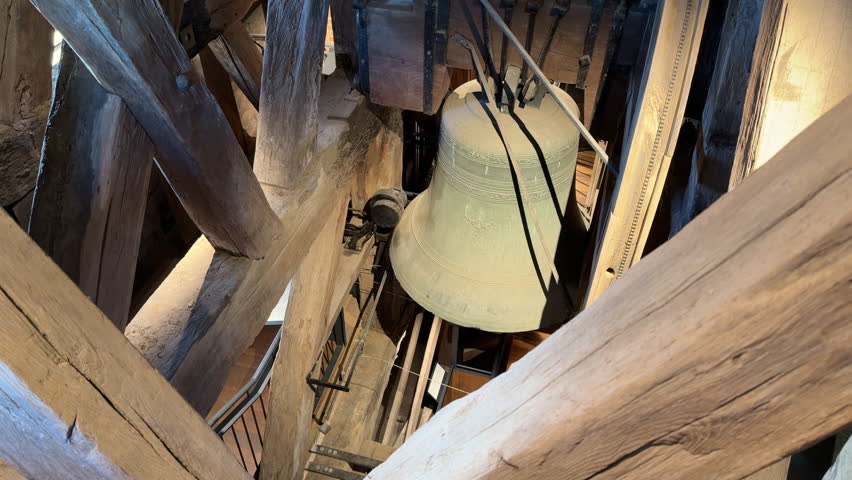 Close-up Of Interior Of Historic Wooden Clock Tower, With Large Aged Metal Bells Hanging From Timber Beams. tilt-up shot