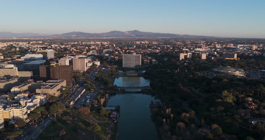 Aerial view of buildings and a lake with a mix of dark and light tones under the sky, portraying urban landscape, Rome, Lazio, Italy.