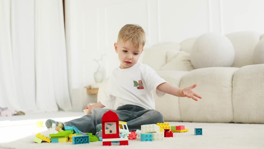 Young child engages with various building blocks on a light carpet in a well-lit living room, featuring a soft sofa and decorative elements