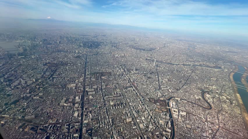 High angle aerial view of Tokyo city skyline stretching towards Mount Fuji under a clear blue sky in Japan.