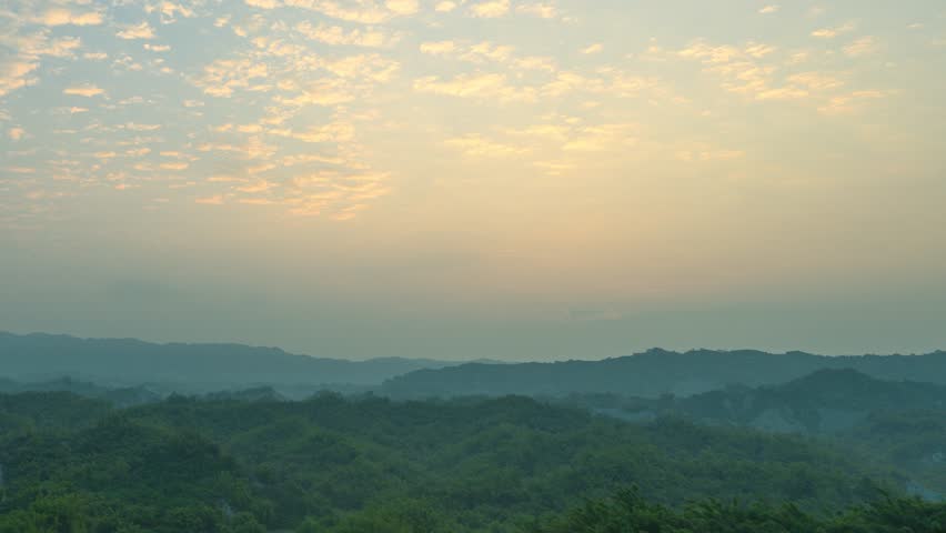 A breathtaking sunrise over the rolling hills of Erliao in Tainan, Taiwan, featuring soft morning light and a cloudy sky.