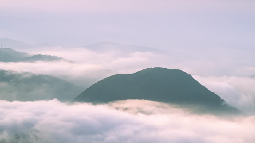 A scenic view of Datun Mountain in Taipei, Taiwan, during a spring morning with thick clouds and mist rolling over the peaks.