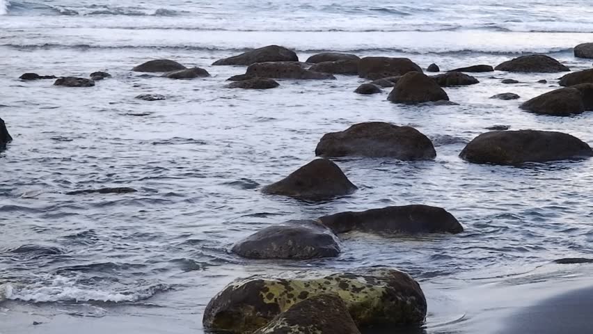 The sound of the waves crashing on the beach in the morning with rocks on the shore at Pangasan Beach, East Java, Indonesia