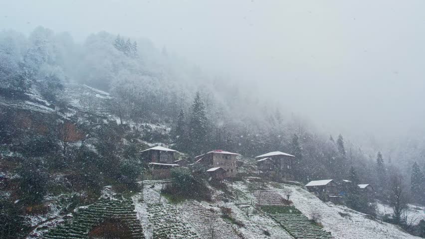 Snowfall covering traditional houses on the mountain slopes of Ayder Plateau in Rize, Turkey. Peaceful winter landscape with misty forests, rural village life, and scenic nature in the Black Sea region.