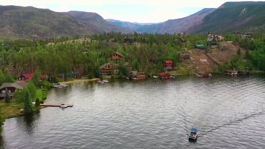 Aerial view of Coeur d Alene Idaho with forested shoreline homes, broad blue lake water, and mountain terrain surrounding an attractive lakeside residential area in summer sun