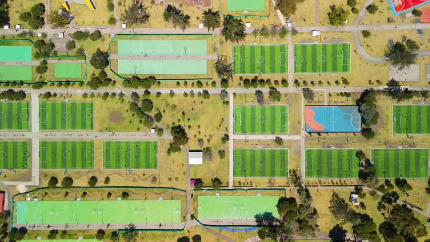 Top-down aerial flyover of Parque La Carolina Quito revealing dense grid of green futsal fields and sports courts