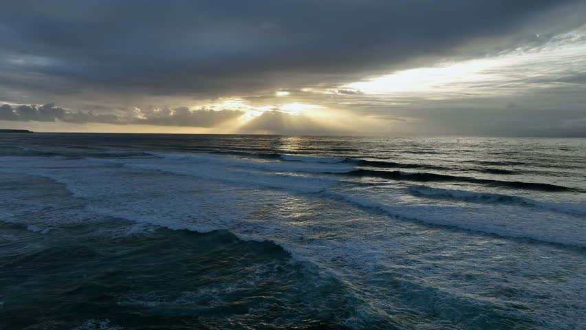 Sunset over a remote sandy beach with cliffs and ocean waves along the west coast in Europe.