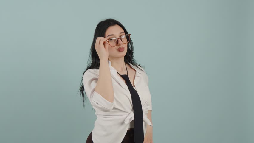 Playful young woman posing with glasses in studio