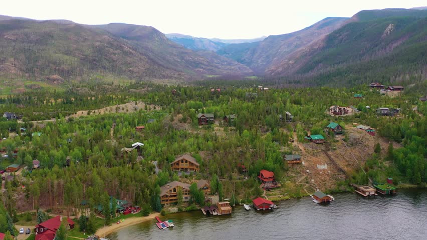 Aerial view of Lake George New York with forested shoreline homes, calm blue water, and rolling mountain ridges around a picturesque lakeside residential community in summer light