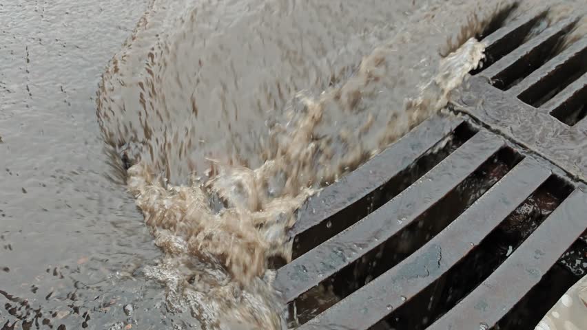 Rainwater flowing into street drain during storm 