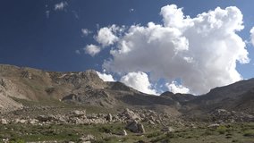 Time lapse of partly cloudy sunny skies above treeless stony hills in the Andes mountains. Sunlit cumulus drift over barren rocky highlands along a rugged Andean cordillera landscape. - Powered by Shutterstock - Get 15% off with code: PIKWIZARD15