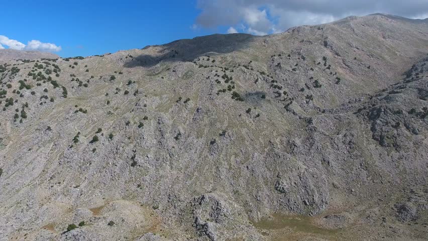 Aerial drone flight over rocky slopes of the Ethiopian Highlands near Simien Mountains peaks. Skyborne ascent above stony Abyssinian uplands around Ras Dashen summits and sparse trees.