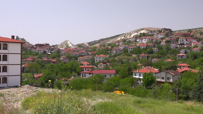 Panoramic view of Beypazari traditional houses across a sunny valley in Ankara, Turkey. Historic Anatolian townscape displays Ottoman homes, cultural heritage, bright daylight atmosphere.