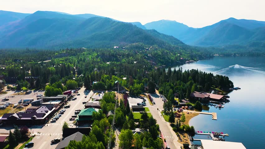 Drone footage of Grand Lake Colorado showing a tranquil lakeshore community, marina piers, mountain landscape, and forested hills wrapping around the bright blue lake
