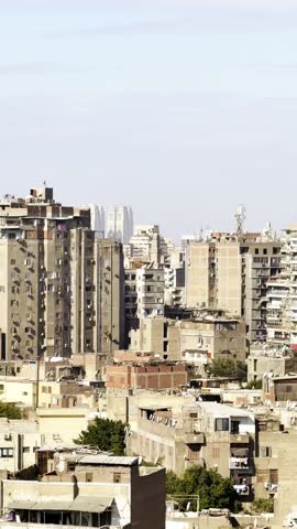 A panoramic view of Old Cairo in Egypt showcases historic buildings, minarets, and rooftops under a cloudy sky. The scene reflects the rich architectural heritage of the city.