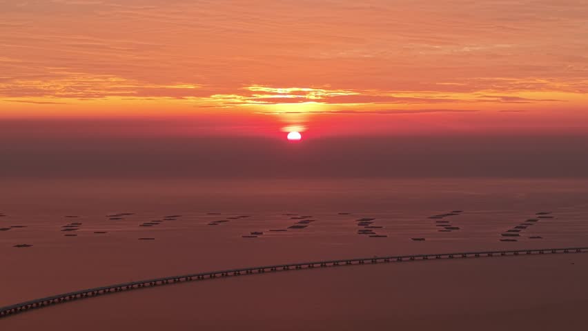 Aerial view of Penang Second Bridge glows in golden sunset hour, stretching gracefully across the horizon.
