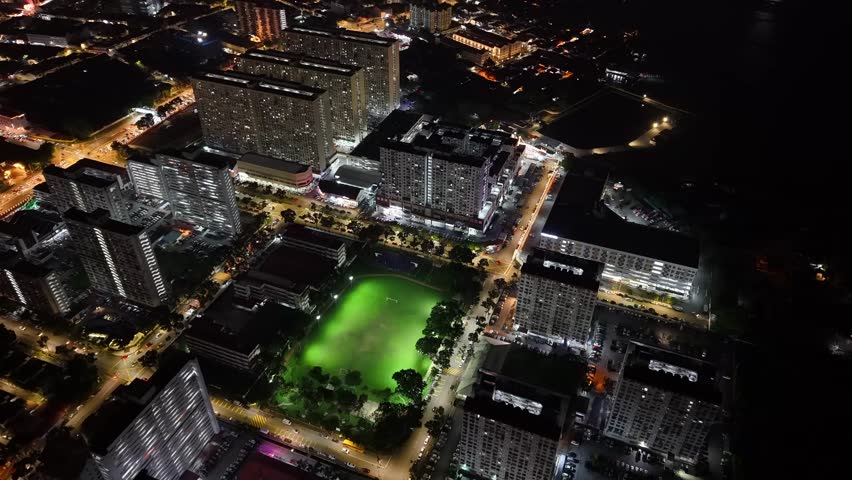 View from sky birdseye night view of Macallum residential flats, illuminated streets and lit sports field.