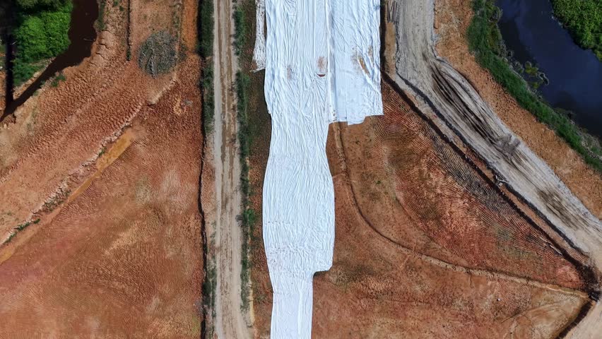 Top-down drone shot of a covered construction area and surrounding wetlands in Batu Kawan.
