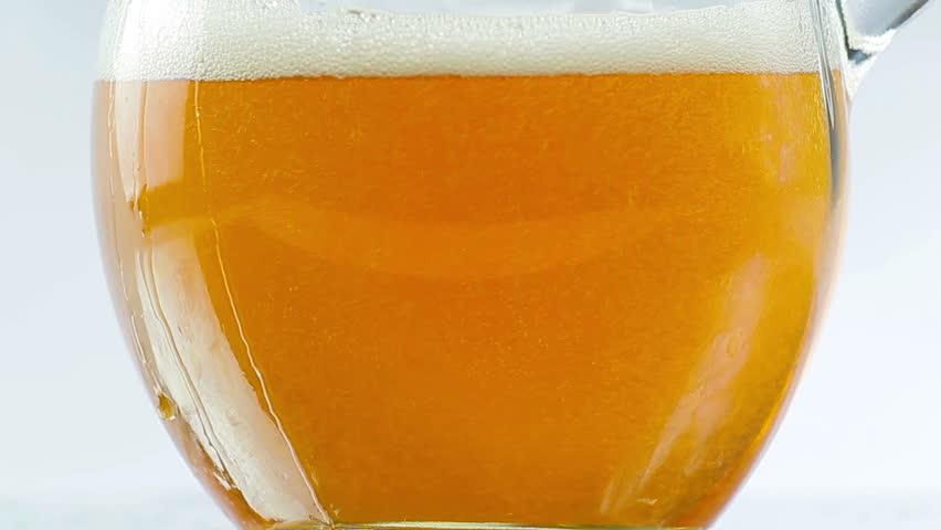 Beer being poured into translucent glass, white isolated background, detailed