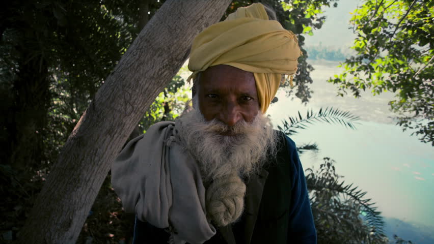 Portrait of a wise old man with a long white beard and a yellow turban standing in nature