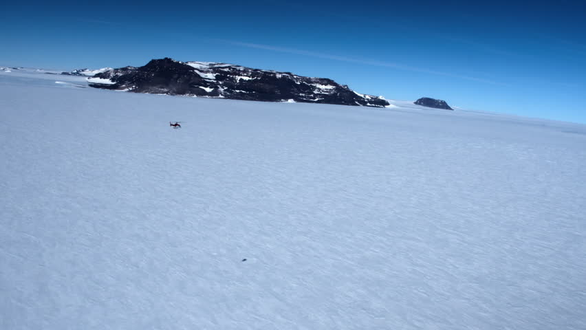 Aerial view of a helicopter flying over an immense icy expanse in Antarctica