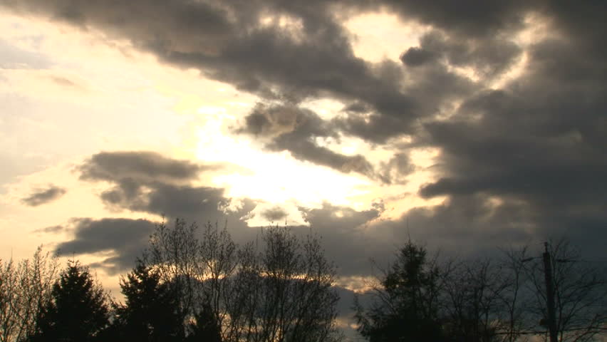 Time lapse during cloudy sunset over tree line in Portland neighborhood with