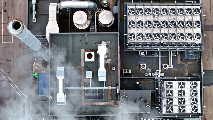 Aerial ascending birdseye drone shot above industrial power plant with cooling fans, smokestack and energy infrastructure