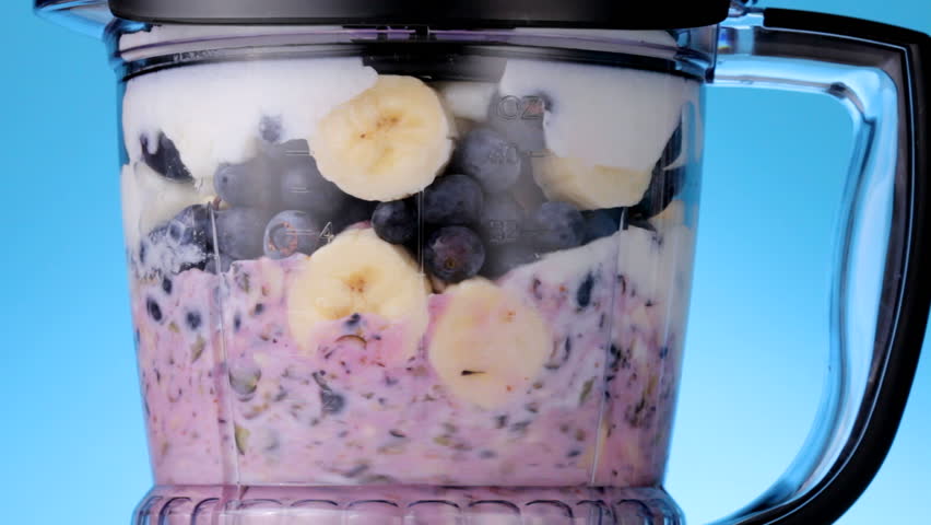 Close up HD video of blueberries and banana slices mixing in a blender to make a