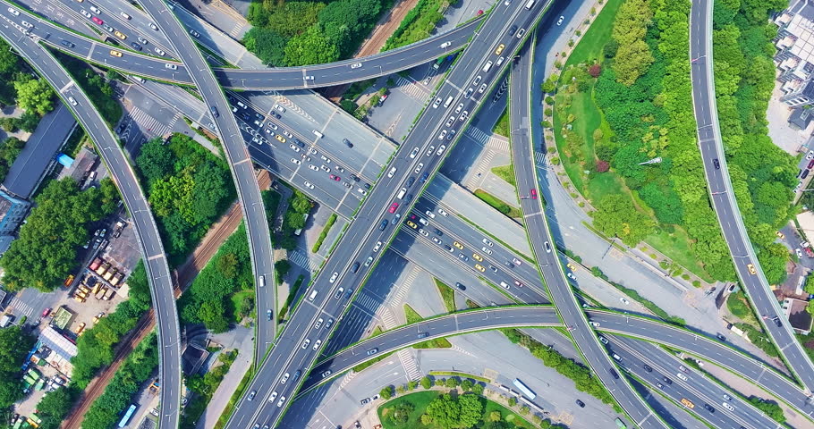 Aerial view of massive urban highway interchange with busy traffic and surrounding green trees in Nanjing, China.