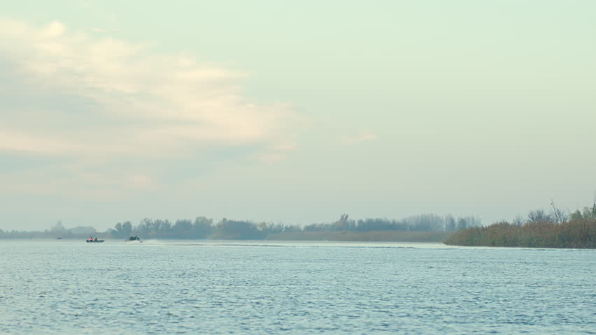 Calm river landscape with distant shoreline and cloudy sky