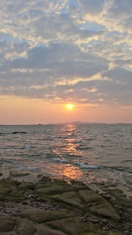 Stunning sunset over the ocean with a vibrant orange sky and calm waves hitting the sandy beach.
