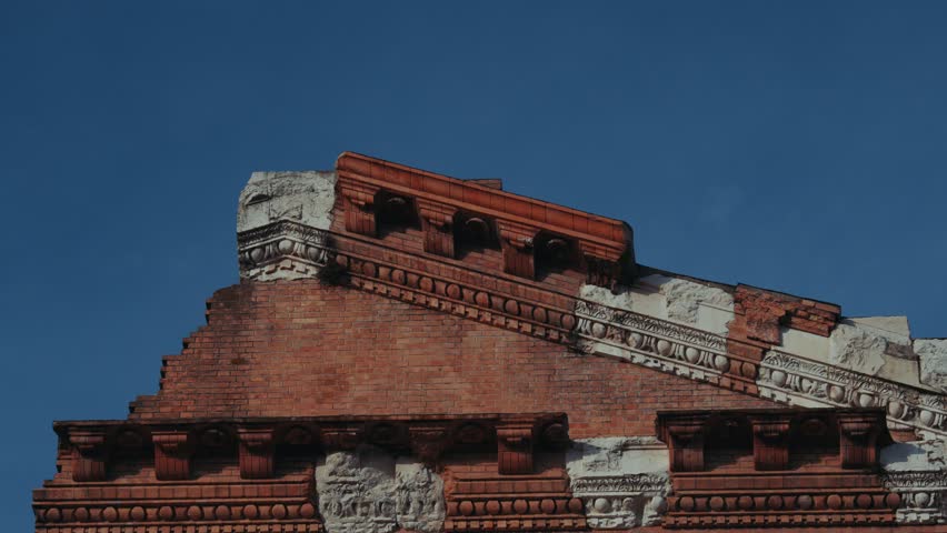 Roman temple facade showing brick architecture and stone relief details against blue sky, Brescia, Italy
