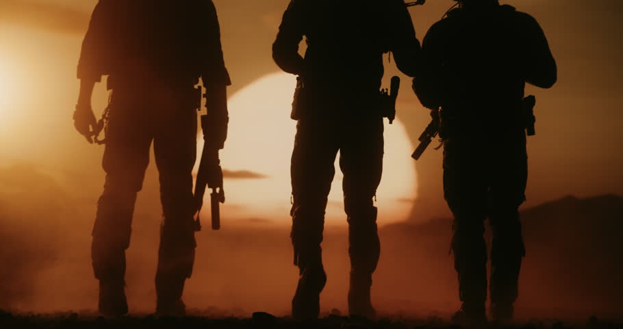 Three Male Peacekeeping Soldiers in Tactical Gear Advance Through a Desert at Sunset. Silhouett of Warriors with Helicopter Air Forces Supports. Cinematic Modern Warfare Patrol Action Mission