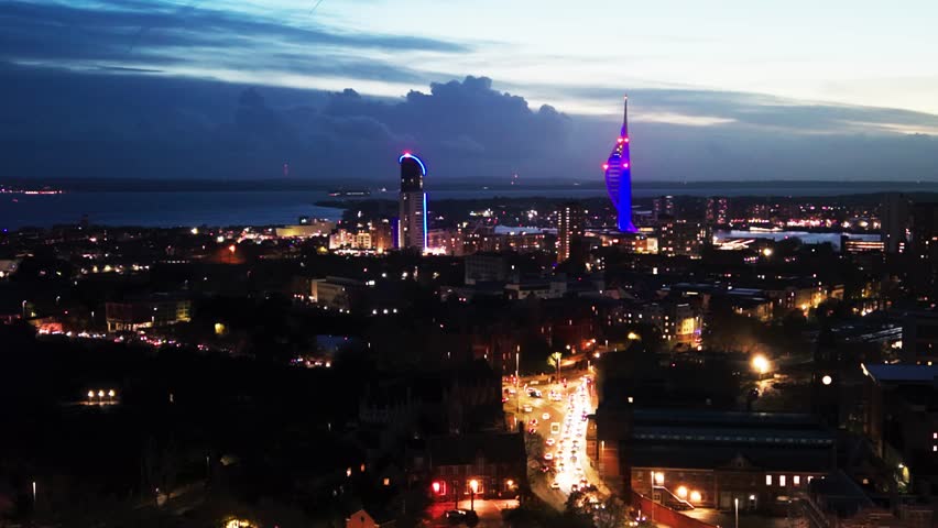 Drone aerial view of Portsmouth skyline at night with illuminated Spinnaker Tower and city lights overlooking Portsmouth Harbour in Hampshire England.
