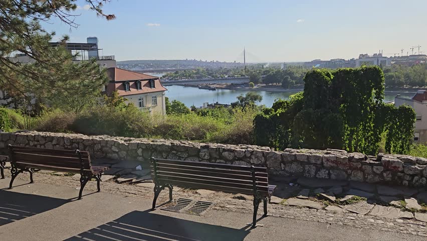 Park with two benches and a view of a river. The benches are empty. Scene is peaceful and relaxing in Belgrade