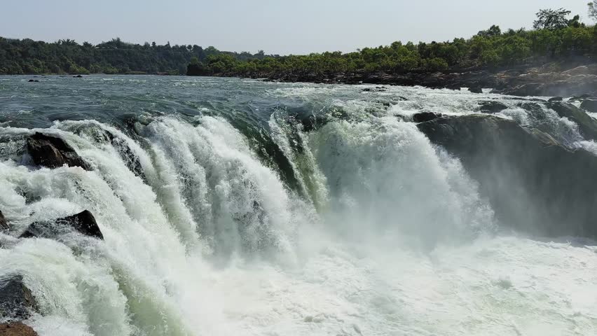 Close up view of powerful waterfall cascading over rocky cliffs with mist and foaming water below, capturing the force of flowing river in a natural landscape.