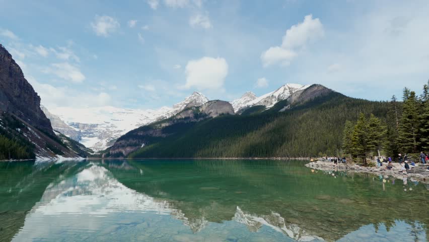Turquoise water of Lake Louise reflecting snow capped mountains and forest in Banff National Park
