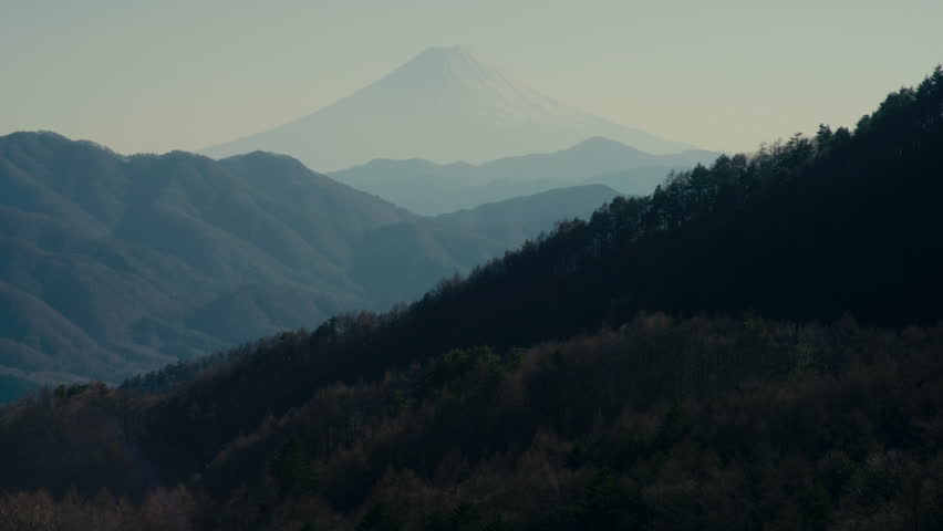 Mount Fuji towering beyond mountain valley landscape in Japan.