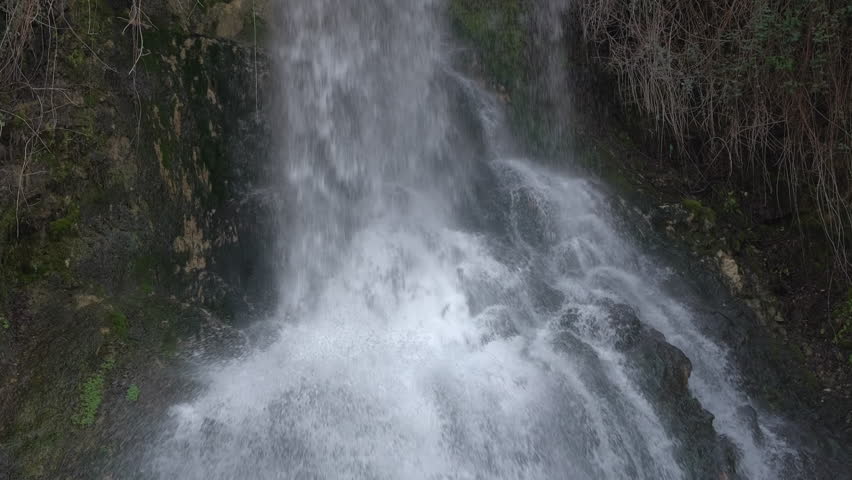 Close-up of streams of water from a waterfall falling and splashing on rocks in spectacular slow motion